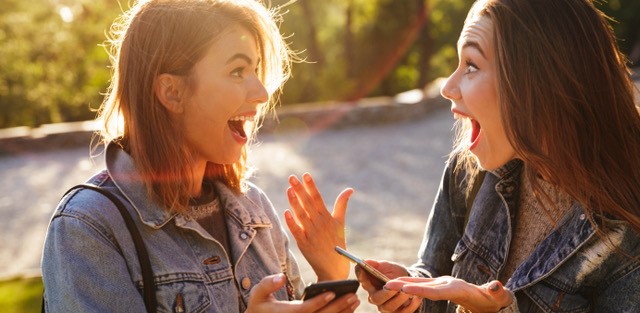 Two young ladies with looking at their cell phones