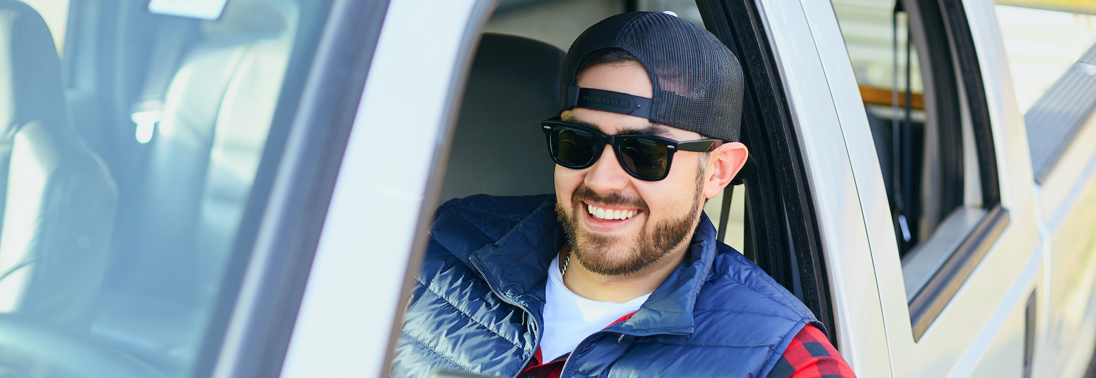 man wearing hat and sunglasses sitting in pickup truck