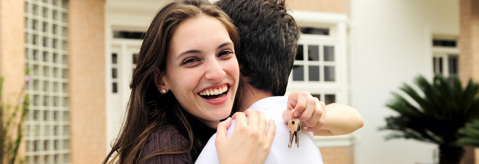 women hugging man and holding keys