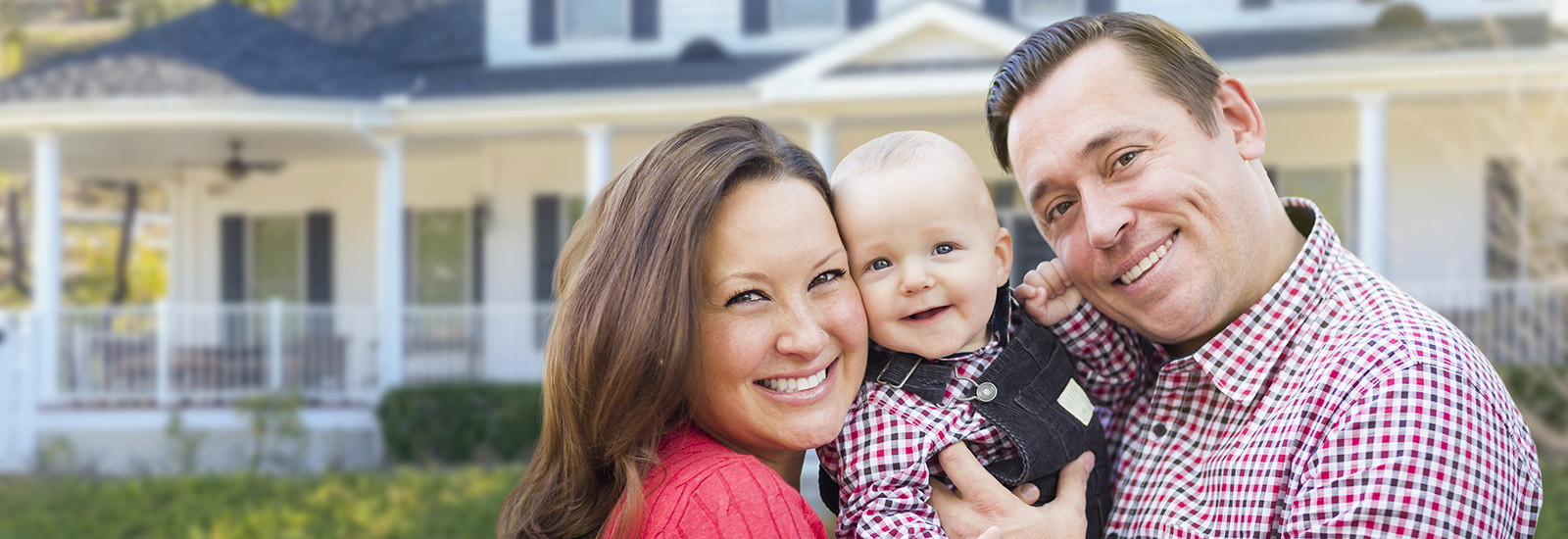 Young family standing in front of new house