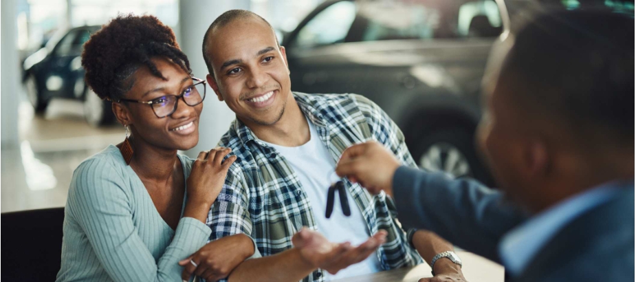 Man handing car keys to young couple