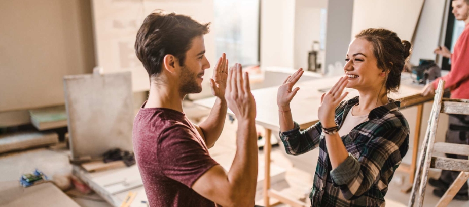 Young couple doing home remodeling clapping hands