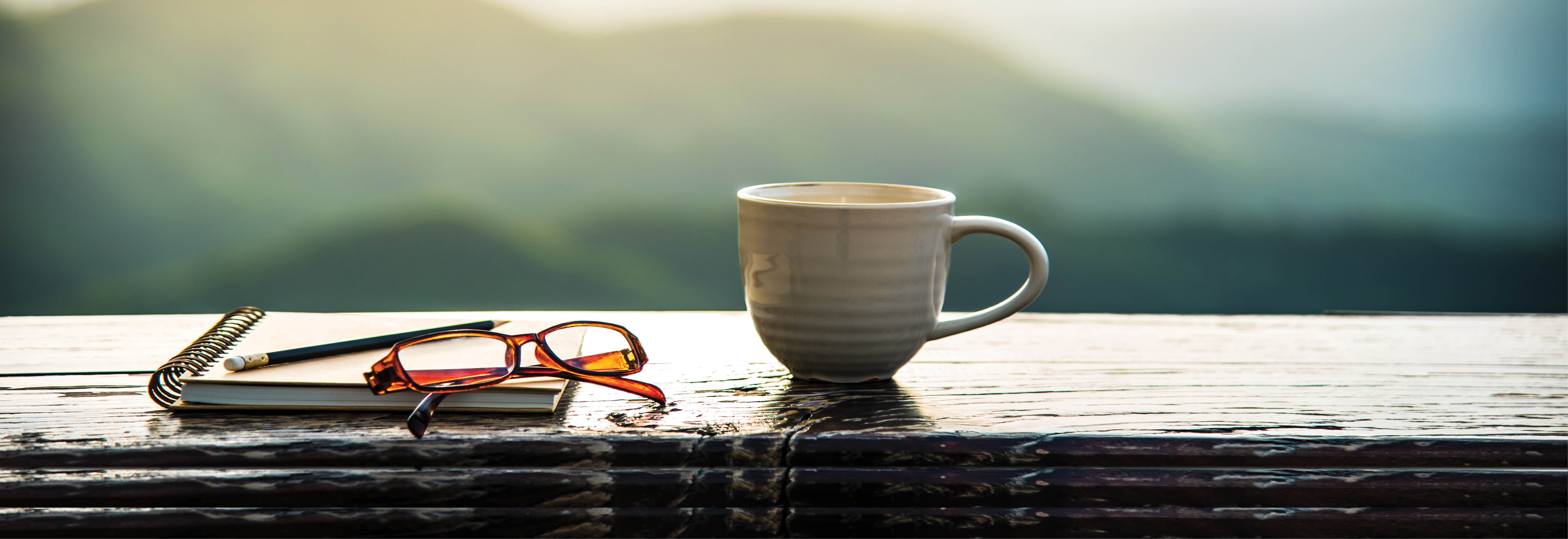 coffee mug, note pad and glasses on porch railing