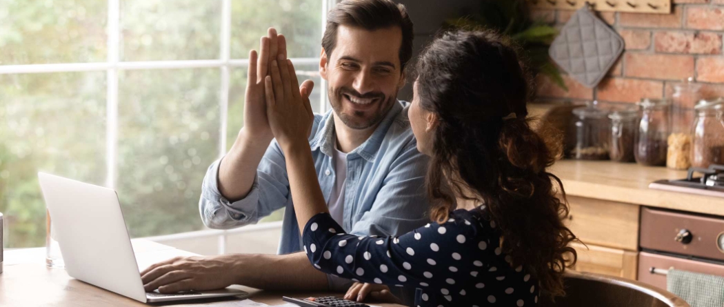 Man and women working on laptop clapping hands