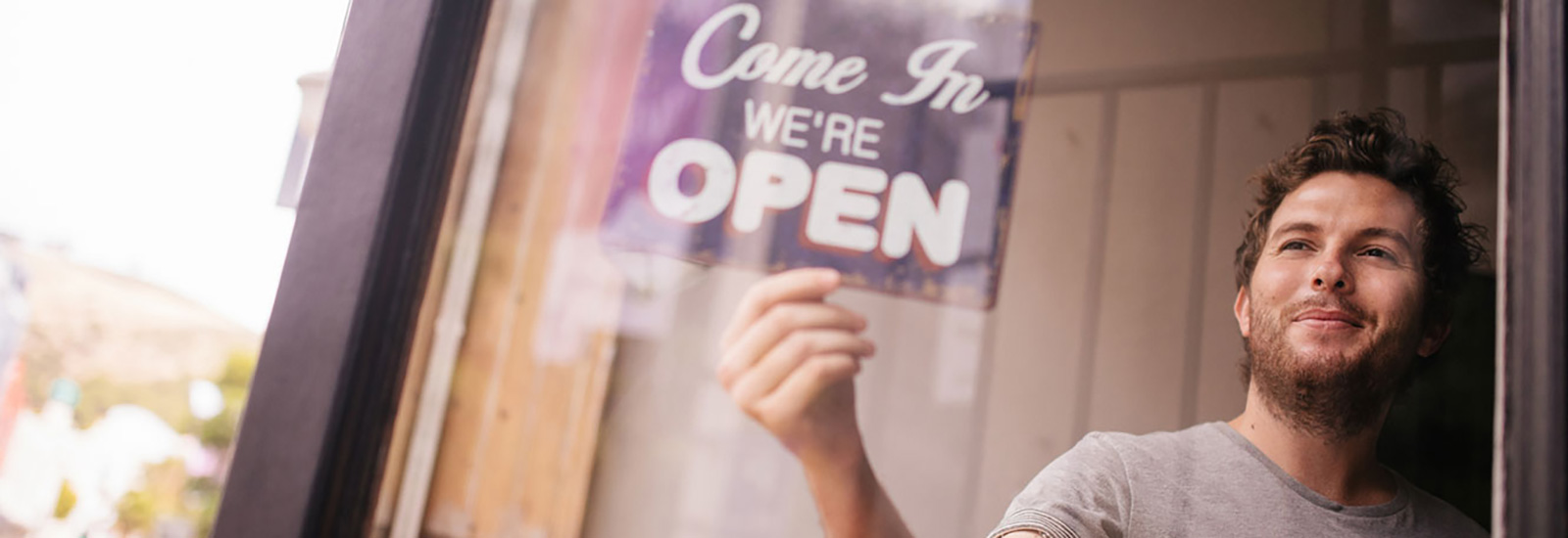 Business owner flipping sign to say come in we are open