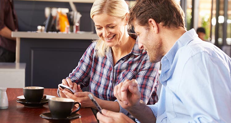 Couple having coffee and looking at cell phones