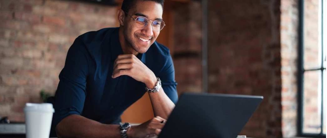 man looking at laptop and having a cup of coffee
